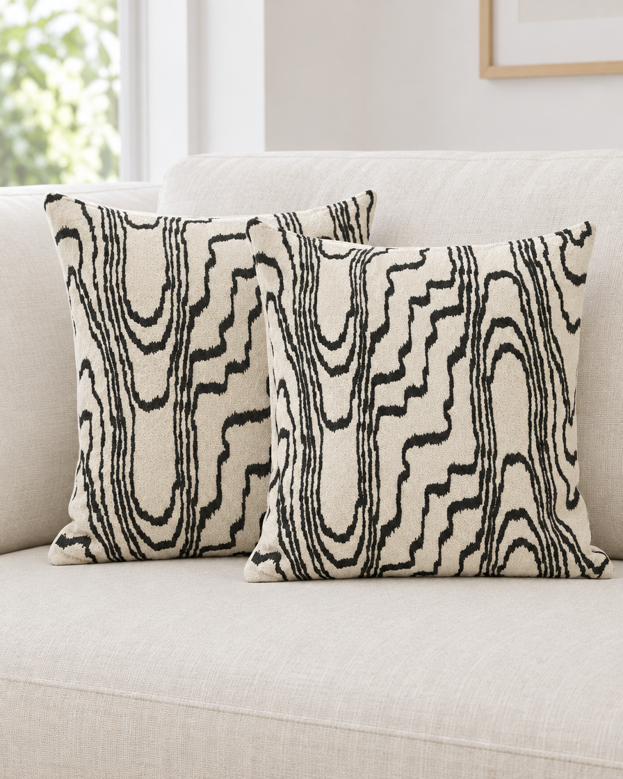 Two ivory and black Wood Grain Embroidery cushion covers on a cream linen sofa