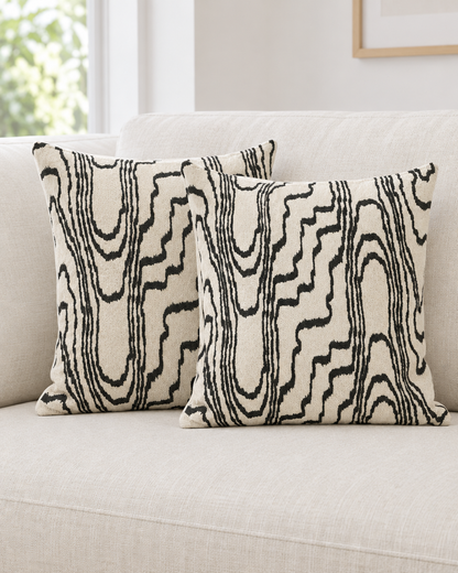 Two ivory and black Wood Grain Embroidery cushion covers on a cream linen sofa