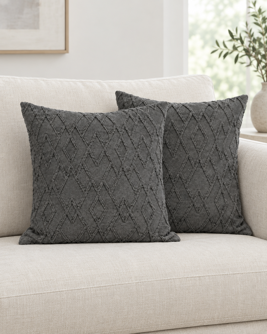 Two charcoal Trellis Jacquard Cotton cushion covers on a cream linen sofa
