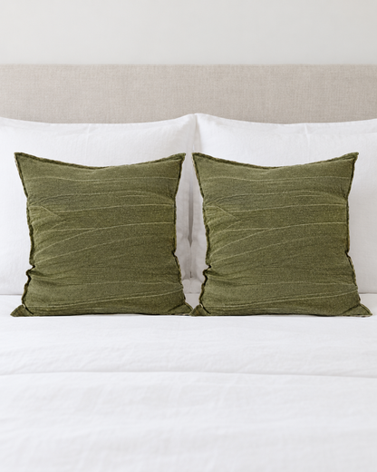 Two Olive Jacquard Linen Cotton cushion covers on a made bed with white bedding