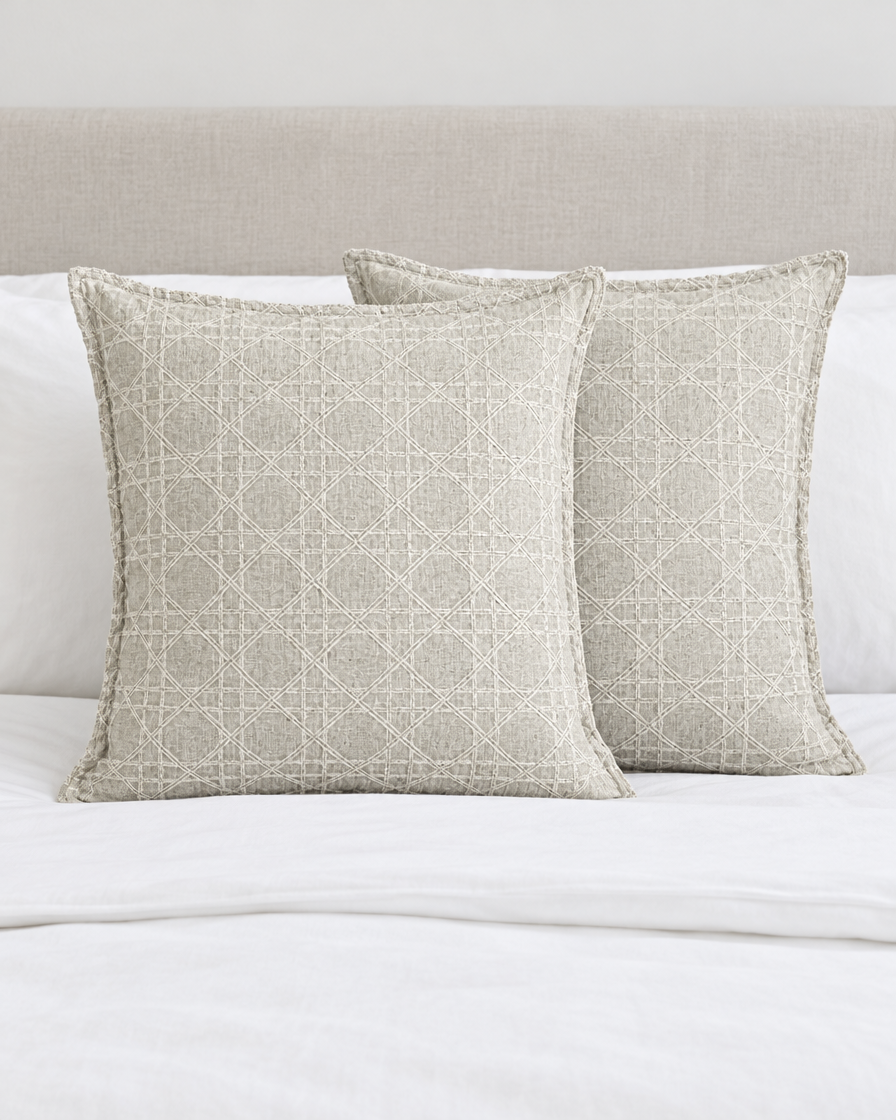 Two Mint Grey Lattice Jacquard cushion covers on a made bed with white bedding