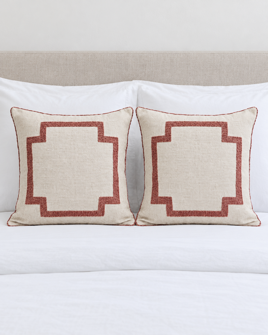 Two Ivory & Rose Embroidery cushion covers on a made bed with white bedding