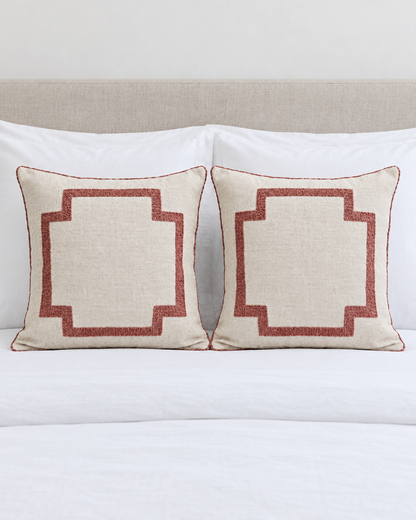 Two Ivory & Rose Embroidery cushion covers on a made bed with white bedding