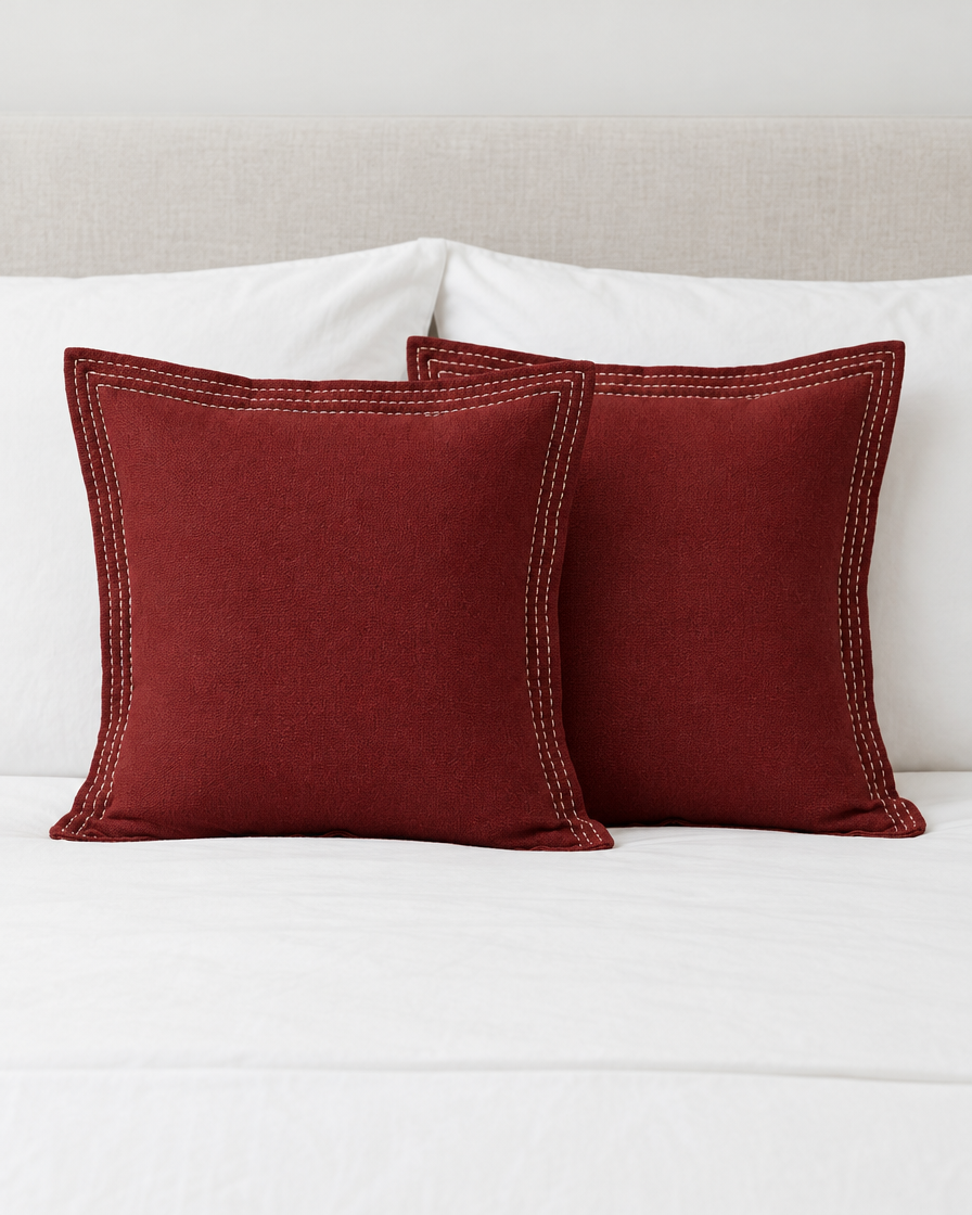Two Burgundy Border Embroidery Ramie Cotton cushion covers on a made bed with white bedding