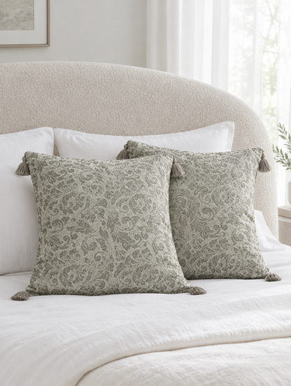 Sage and ivory grape leaf jacquard cushions with corner tassels on ivory bedding by a curved boucle headboard