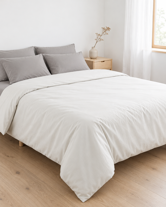 Minimalist bed in off white and light grey cotton in a pale Scandinavian bedroom