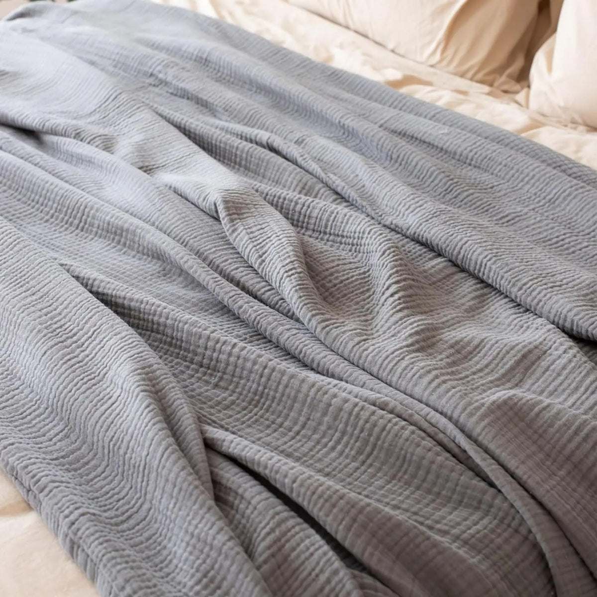 Close-up of the soft drape and crinkled texture of a grey muslin throw