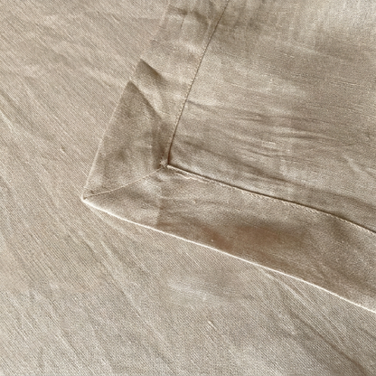 Close-up of the mitred corner and double-turned hem on a natural linen tablecloth