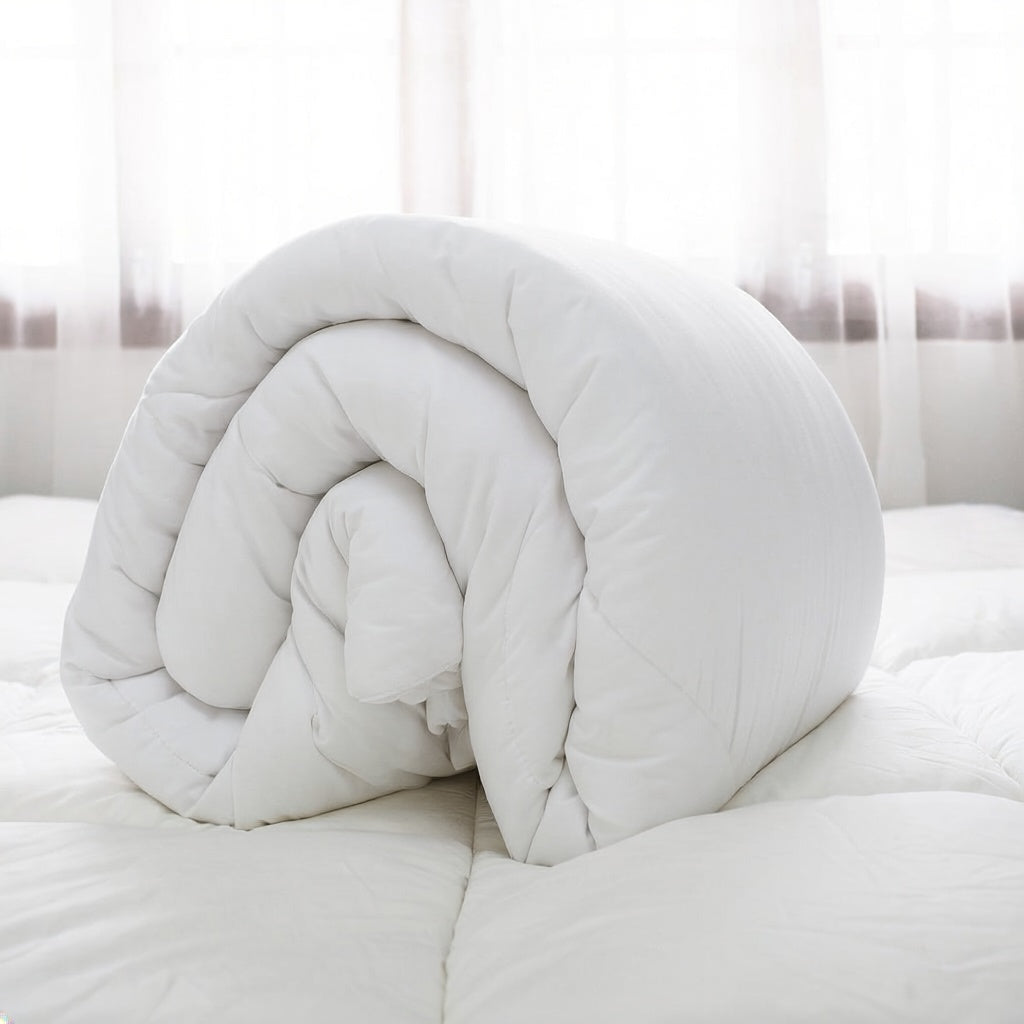 White duvet insert rolled on a bed beside a window.