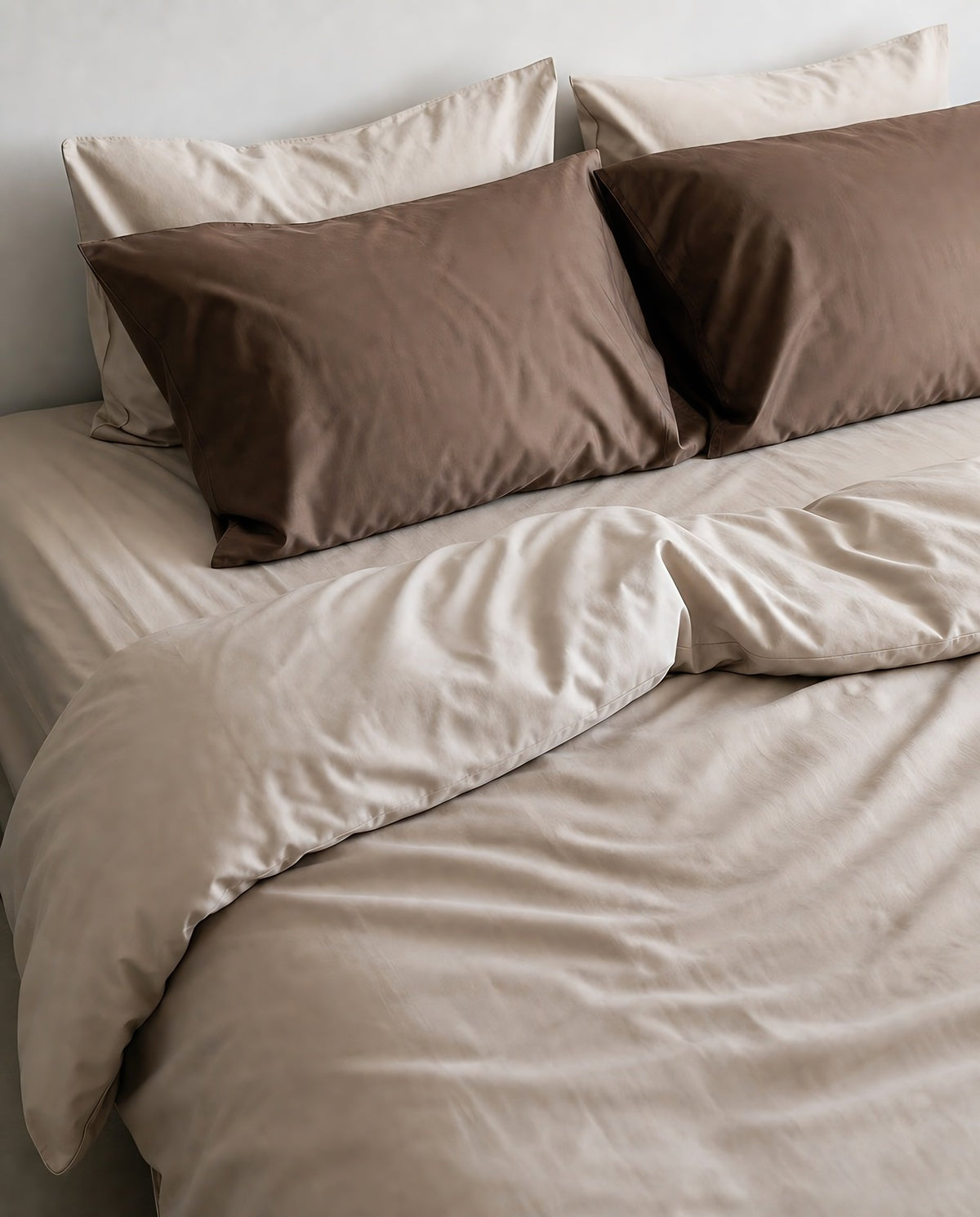 Taupe and brown silky cotton bedding set on a made bed