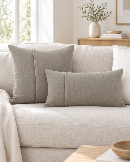 Stone jacquard square and long lumbar cushions with a frayed cord seam on an oatmeal linen sofa in a calm living room