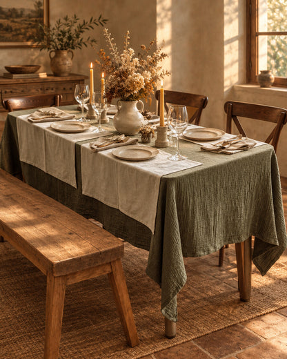 Juniper green cloud cotton table cloth draped low over a long dining table laid for six, with a wooden bench
