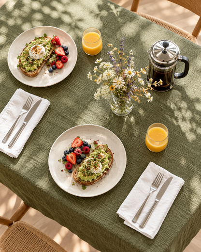 Juniper green Cloud Cotton tablecloth on a brunch table from above, with avocado toast, juice and wildflowers