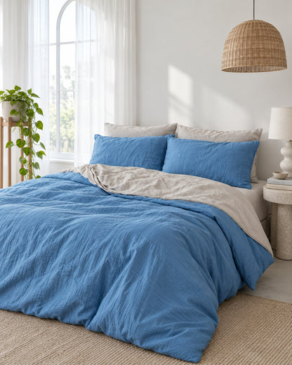 Blue and cream two-tone cloud cotton bedding beneath an arched window with a trailing pothos and rattan pendant