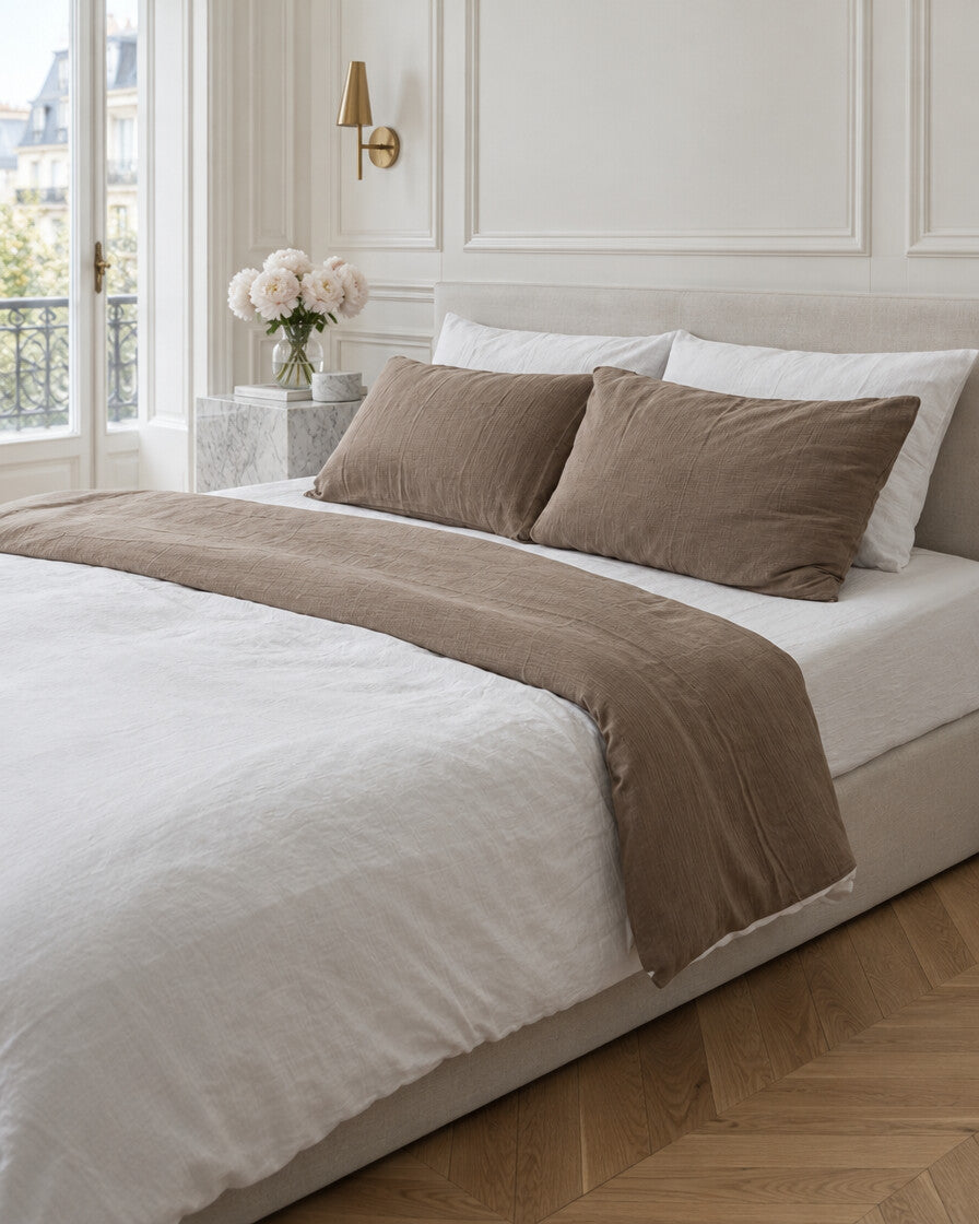 Mocha and white two-tone cloud cotton bedding in a Parisian bedroom with panelled walls and fresh peonies