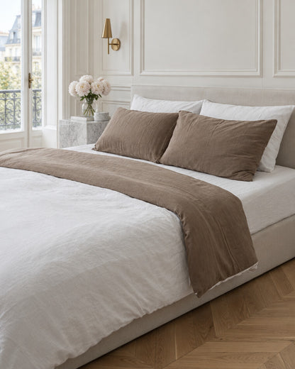 Mocha and white two-tone cloud cotton bedding in a Parisian bedroom with panelled walls and fresh peonies
