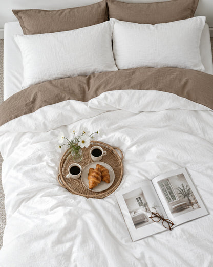 White and mocha two-tone cloud cotton bedding seen from above with a breakfast tray of coffee and croissants