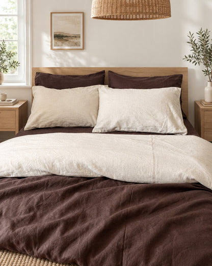 Chocolate brown and cream two-tone plain cotton bedding made up with cream pillows on an oak bed