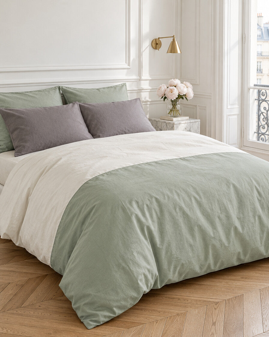 Sage green and cream two-tone plain cotton bedding in a Parisian bedroom with panelled walls and fresh peonies