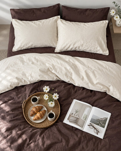 Chocolate brown and cream two-tone plain cotton bedding seen from above with a breakfast tray of coffee and croissants