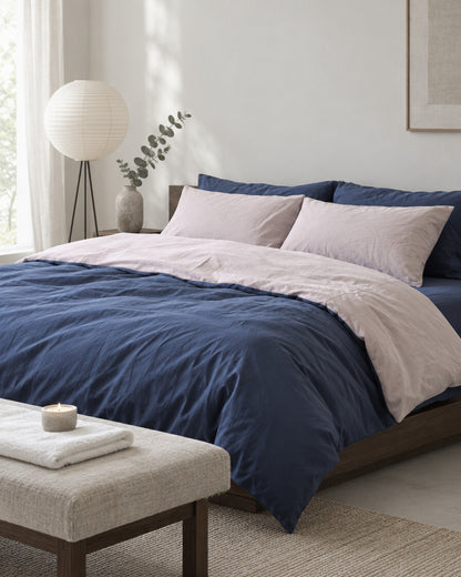 Navy and blush pink two-tone plain cotton bedding in a calm Japandi bedroom on a low dark-oak bed