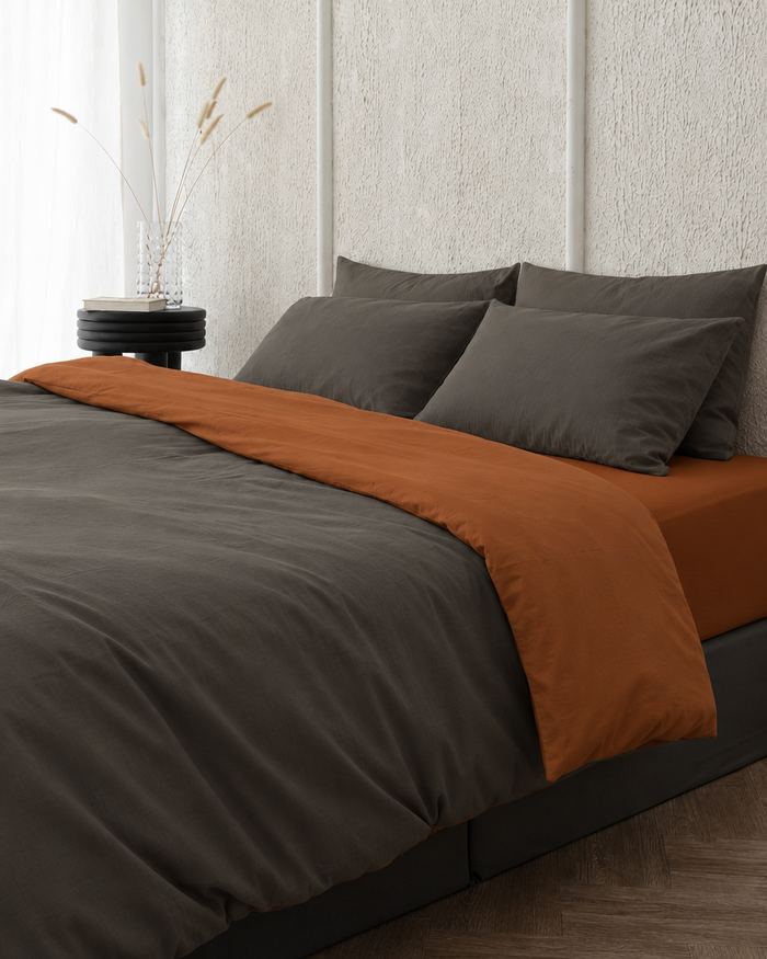 Two tone Plain Cotton duvet cover in Charcoal Grey folded back to show a terracotta reverse