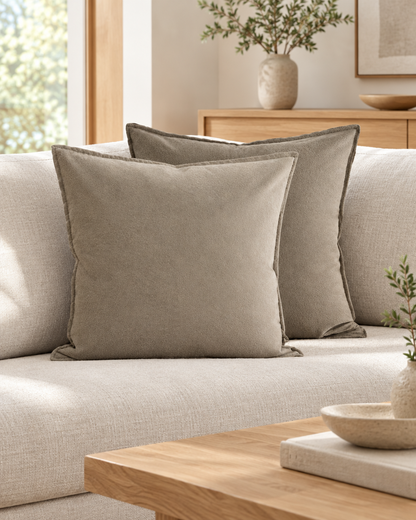Two taupe two-tone flannel cushion covers with flat flange edges on a sofa beside a low oak table
